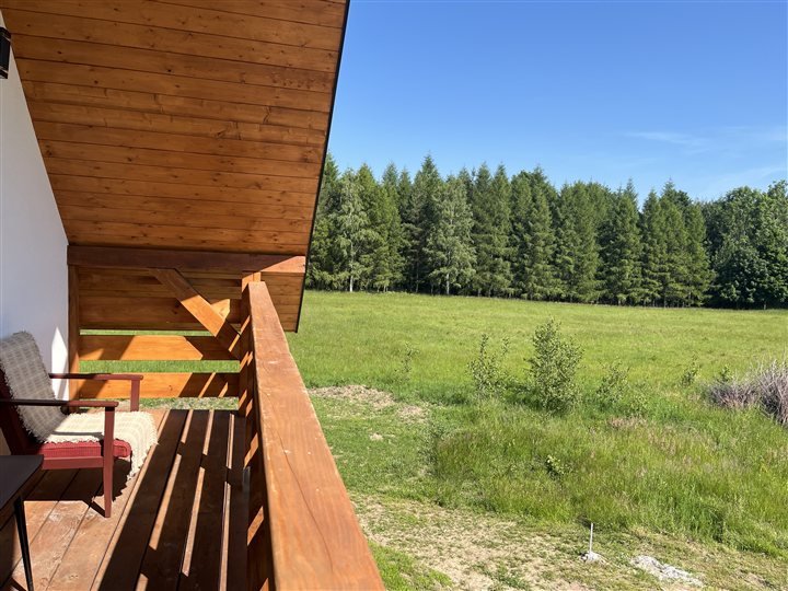 Drewniany balkon z widokiem na łąkę i las