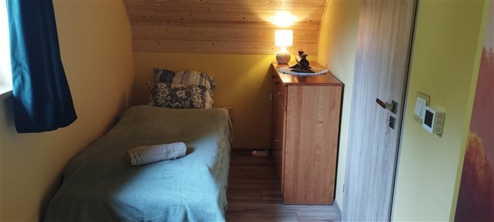 Pokój z pojedynczym łóżkiem i drewnianą komodą